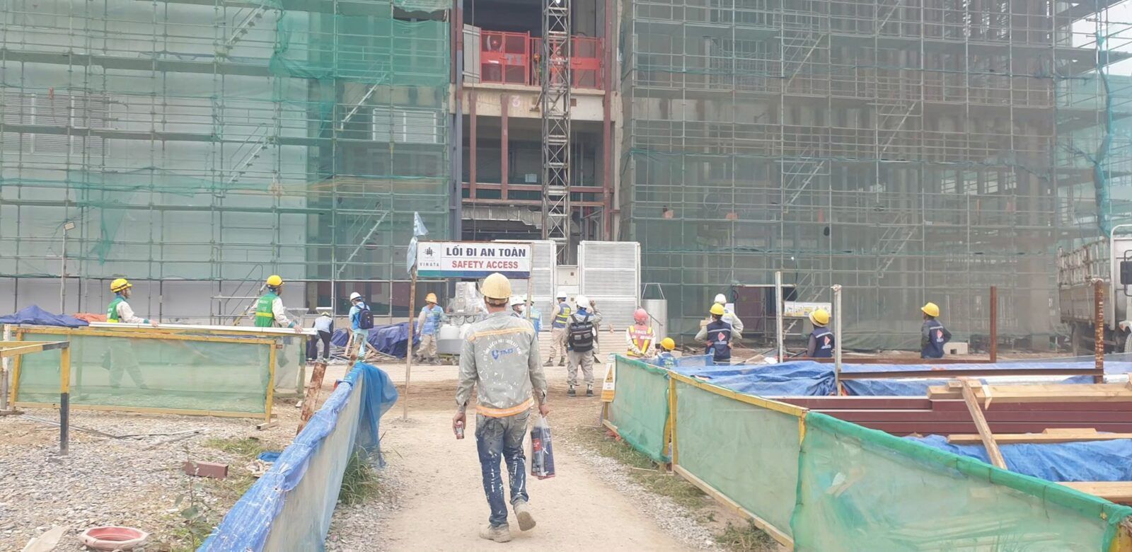 Lối đi an toàn vào công trường, đội thi công đội mũ bảo hộ đi vào khu nhà đang dựng